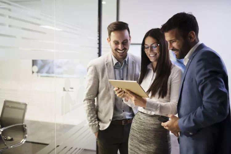 Trois collaborateurs travaillant ensemble sur une tablette dans un bureau