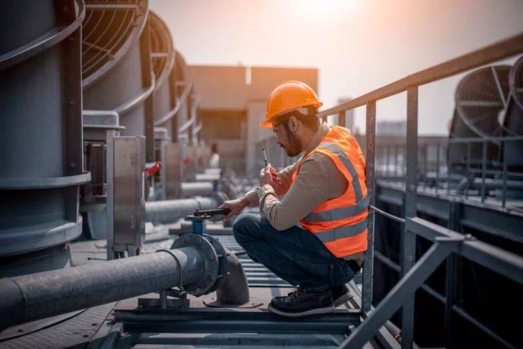 Travailleur sur un toit s'occupant de l'entretien d'un système de climatisation