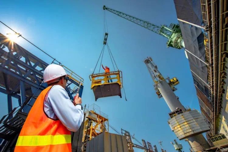 Travailleur sur un chantier regardant une nacelle déplacée par une grue