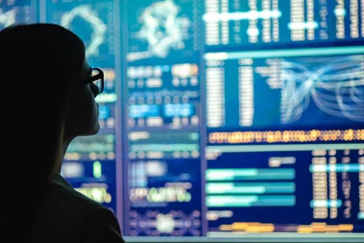 Femme en train de regarder et d'analyser des courbes et des graphiques s'affichant sur un écran