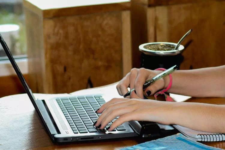 Jeune femme rédigeant une lettre de motivation sur son ordinateur portable