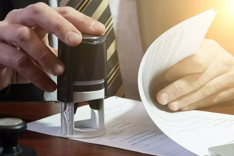 Personne en train de tamponner un contrat avec le tampon de l'entreprise