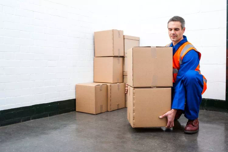 Homme soulevant des cartons en fléchissant les jambes et en gardant le dos droit