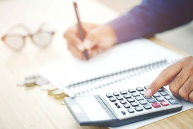 Homme calculant le budget et les dépenses sur une calculatrice