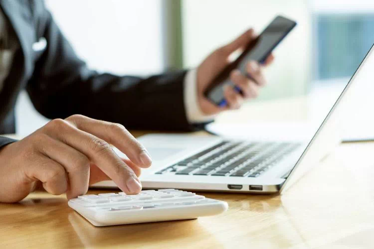 Comptable travaillant avec son téléphone, son ordinateur et sa calculatrice