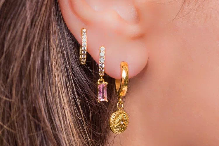 Femme avec les oreilles percées et 3 jolies boucles d'oreille