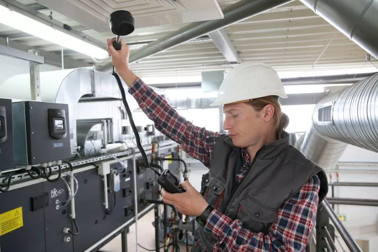 Technicien mesurant la qualité de l'air en dessous d'une climatisation