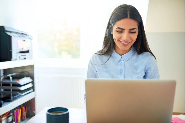 Femme contente devant son ordinateur parce qu'elle trouve solution avec le site web du guichet unique de formalité des entreprises