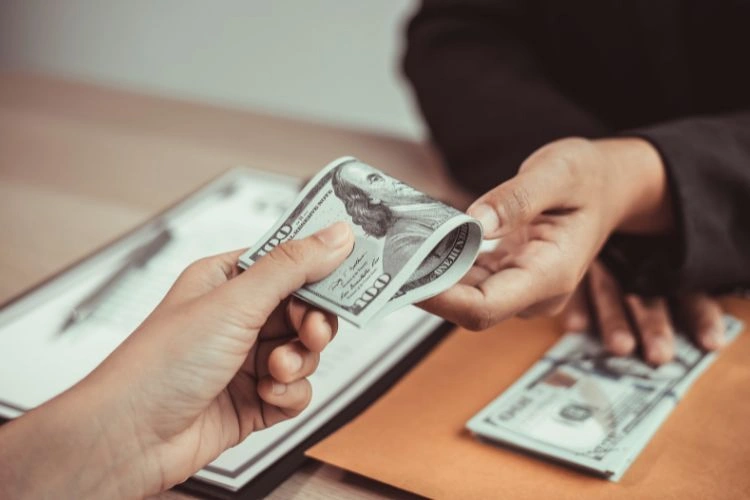 Personne donnant de l'argent à une autre personne représentant la paye d'un ingénieur mécanique