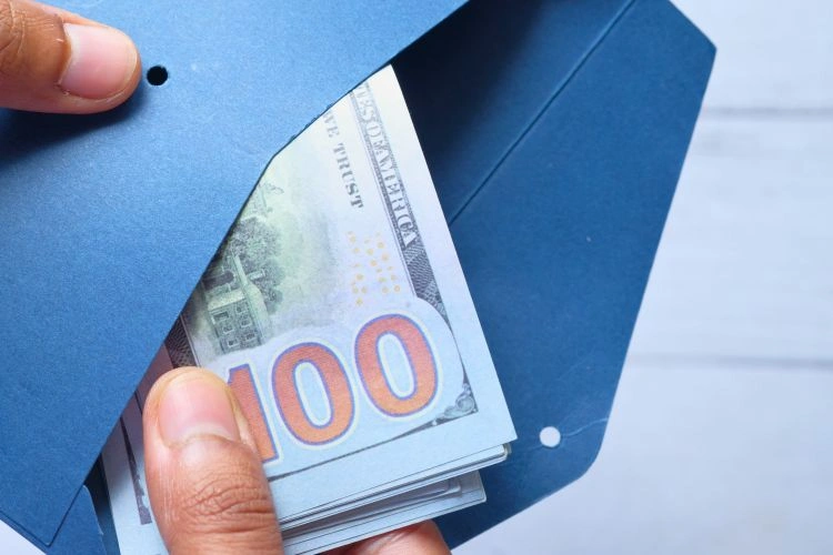 Billets dans une enveloppe représentant les salaires des thanatopracteurs et des croque-morts