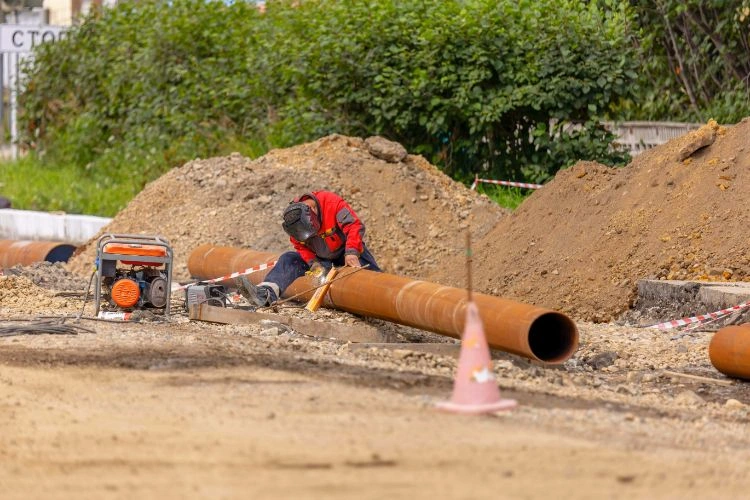 Soudeur en train de travailler sur un tuyau métallique en plein air