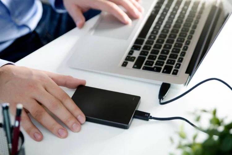 Homme faisant une sauvegarde des données de son ordinateur sur un disque dur externe