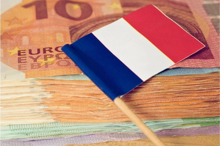 Pile de billets avec un petit drapeau français au-dessus pour représenter les salaires moyens en France par âge