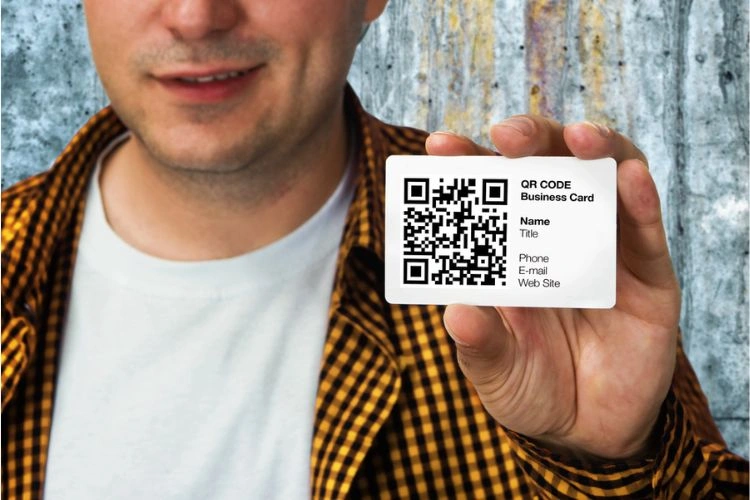 Homme tenant sa carte de visite avec un QR code dessus