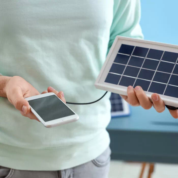Homme rechargeant son téléphone avec un panneau solaire portable
