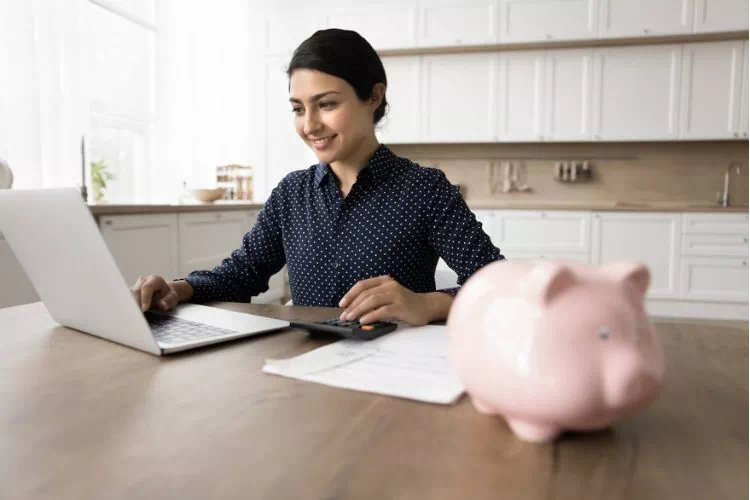 Jeune femme sur son ordinateur mettant de l'argent dans une cagnotte en ligne