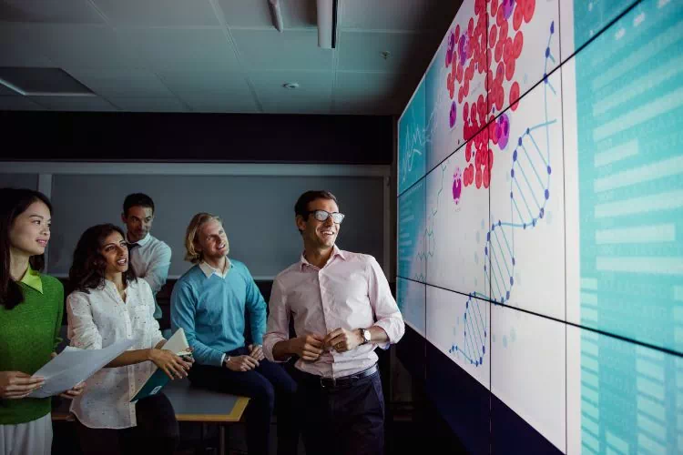 Réunion de collaborateurs devant un écran numérique interactif