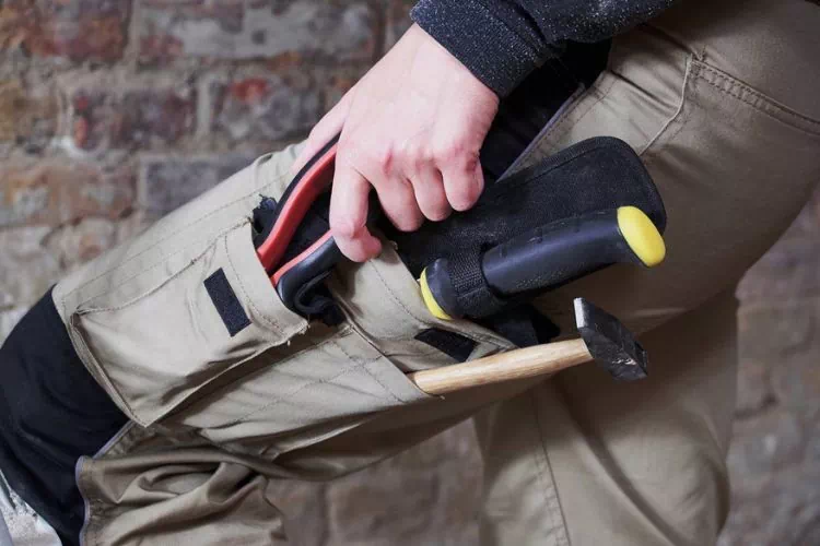 Homme mettant ses outils dans une des poches de son pantalon de chantier