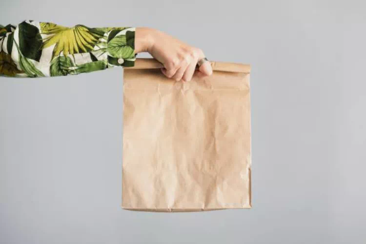 Personne qui tend un sac kraft compact