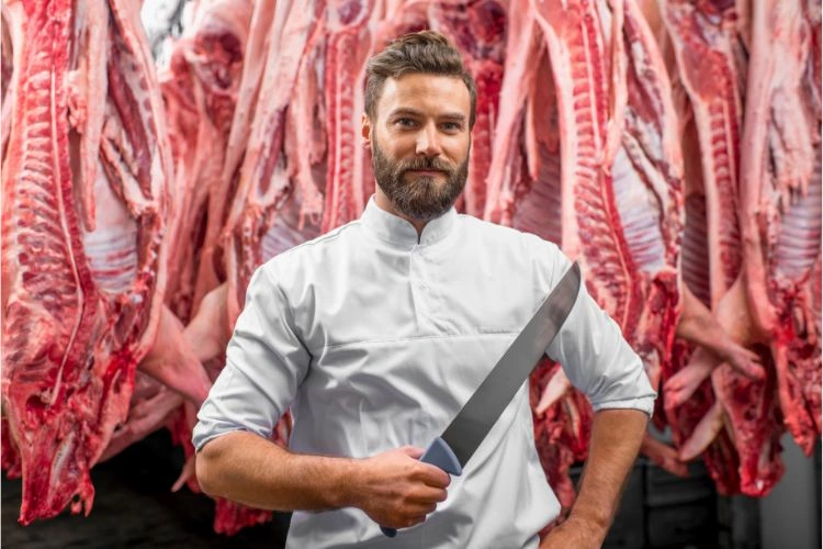 Boucher à coté de viandes suspendues