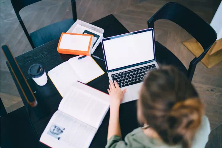 Femme sur son ordinateur en train d'écrire un mémoire