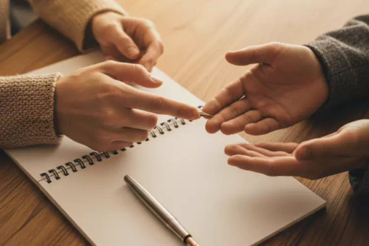 Gros plan sur mains en consultation professionnelle lors d'un bilan de compétences