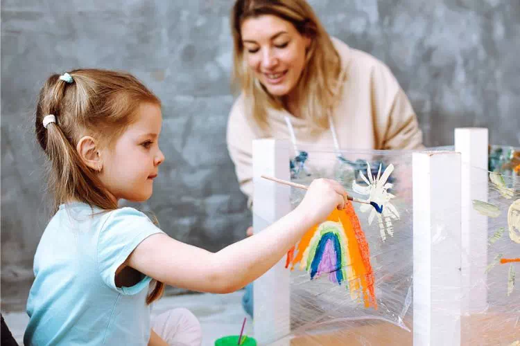 Éducatrice jouant au dessin avec une petite fille